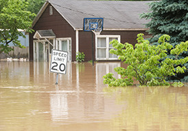 Flooded street with water level almost reaching the top of a speed limit sign