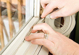 Hands putting insulation/caulking strip around a window