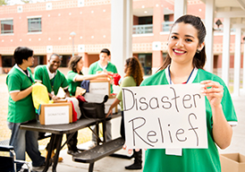 Woman standing outside holding a Disaster Relief sign