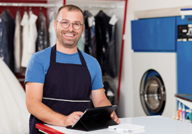 Man in a dry-cleaning business, laptop open on a table