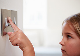 Young girl turning on a light switch