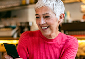 Woman is shown on mobile phone, sitting in a coffee shop and registering for PSE&G's paperless billing program.