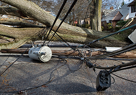 Tangled wires wrapped around a fallen pole on the ground