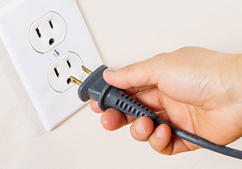 a hand sticking a plug into an outlet