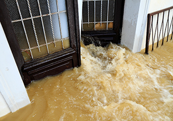 Muddy floodwaters rushing through an open door