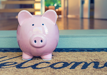 Piggy bank sitting outside on welcome mat