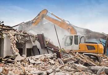 Construction equipment on pile of rubble demolishing house