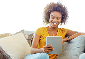 Woman sitting on a couch holding a tablet.