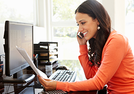 Woman talking on the phone while holding and looking at a paper