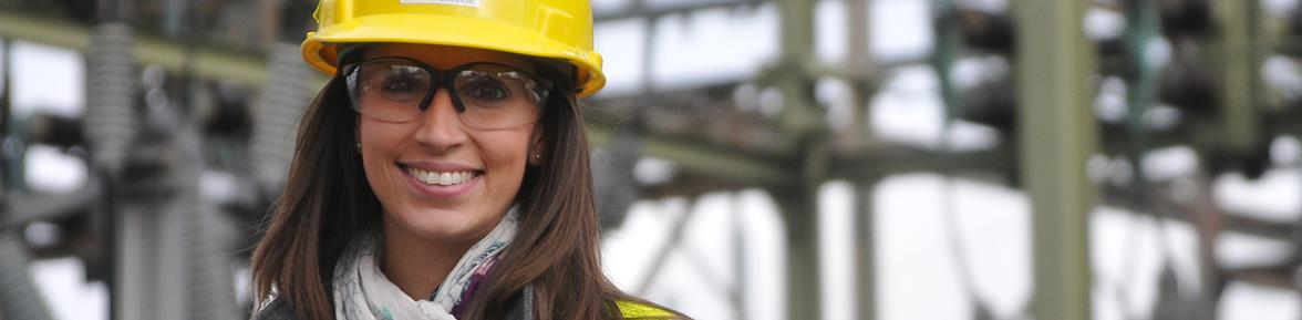 A female PSE&G executive wearing a hard hat in front of a power station