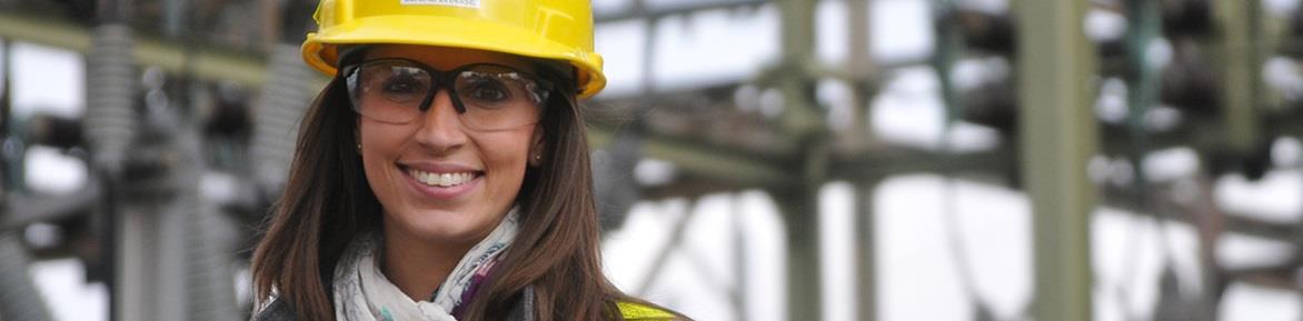 A female PSE&G executive wearing a hard hat in front of a power station