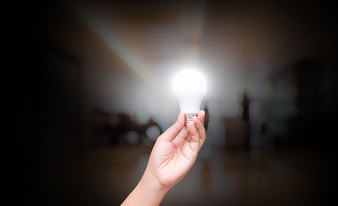 a hand holding an illuminated light bulb