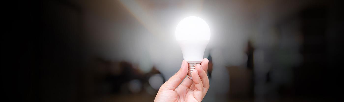 a hand holding an illuminated light bulb