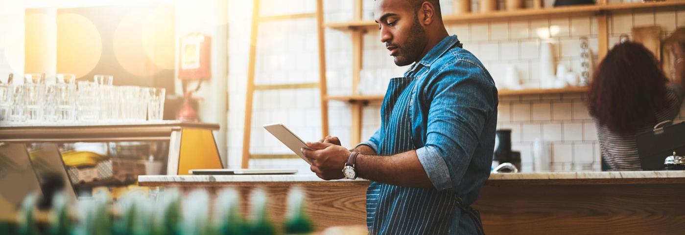 Man in small business cafe using tablet