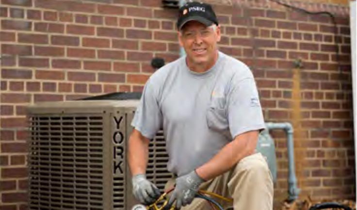PSE&G technician kneeling in front of an HVAC unit