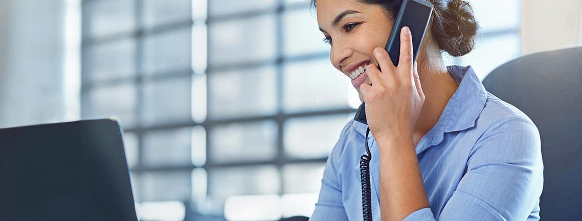 woman smiling walk talking on the phone and looking at a computer