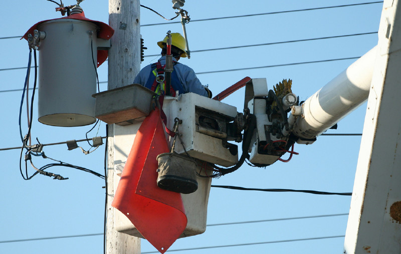 A utility worker in a lift basket examining power lines