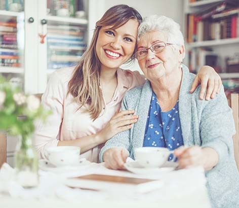 Younger woman sitting next to and wrapping her arms around an older woman