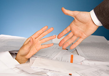 One hand reaching to help another hand that is buried in paperwork