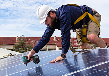 A technician installing solar panels on the roof of a home