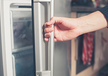 Closeup of a hand opening a refrigerator door