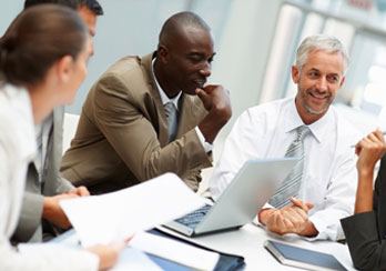 Office workers sitting at a conference table are shown.