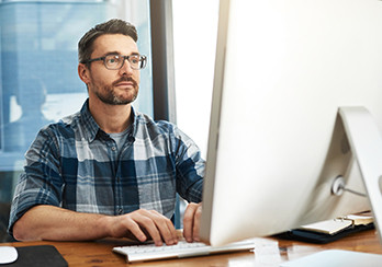 Man sitting at a table working on a desktop computer