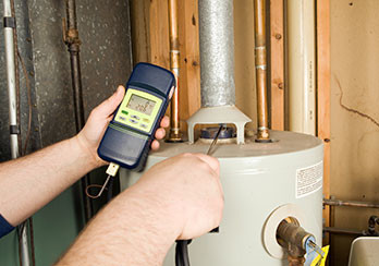 A technician using a device to test for carbon monoxide leaks