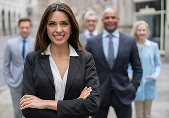 Female executive in the foreground, with a group of other executives behind her