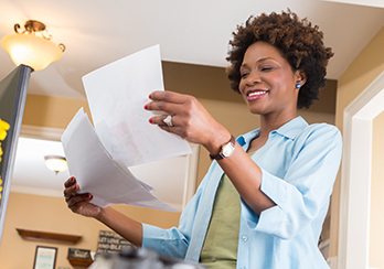 Woman holding several sheets of paper and smiling
