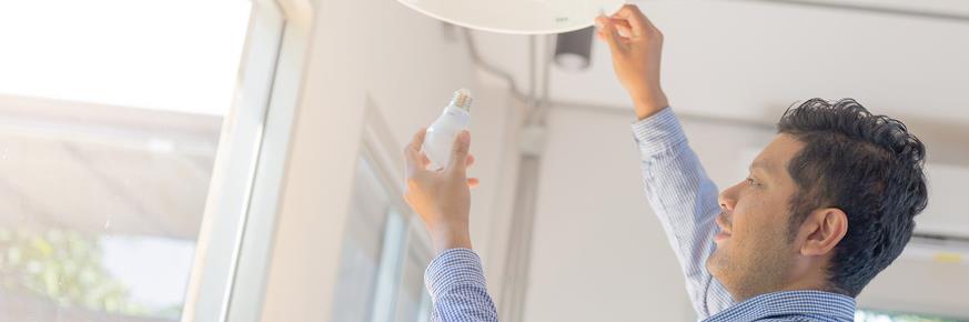 Customer replacing a light bulb with an energy efficient one.