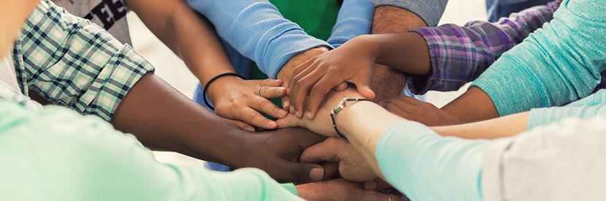 A group of people all putting their hands together in the center of a circle