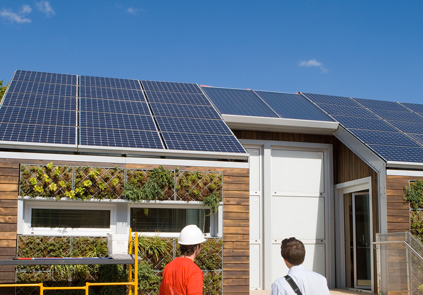 Two men looking up at solar panels installed on a roof