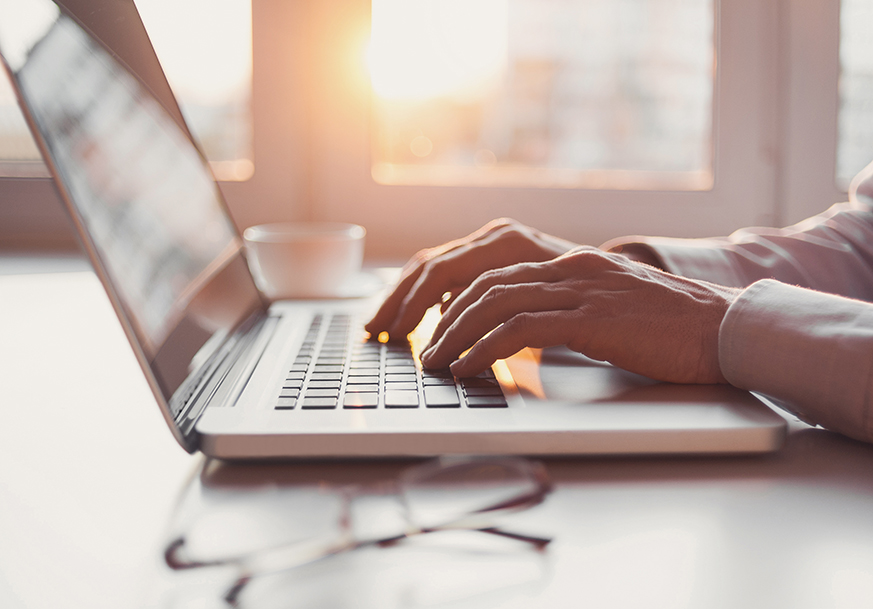An open laptop computer with hands typing on the keyboard