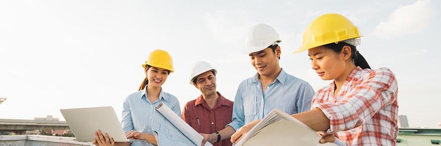 Four building contractors looking at blueprints at a construction site.