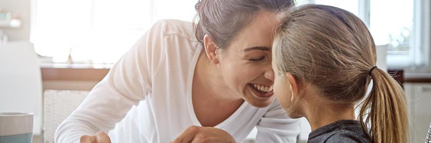 Mother and daughter sitting at kitchen table; eating pancakes