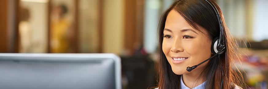 Woman wearing a phone headset, looking at a computer