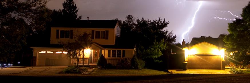 Suburban home under cloudy sky with lightning in the distance