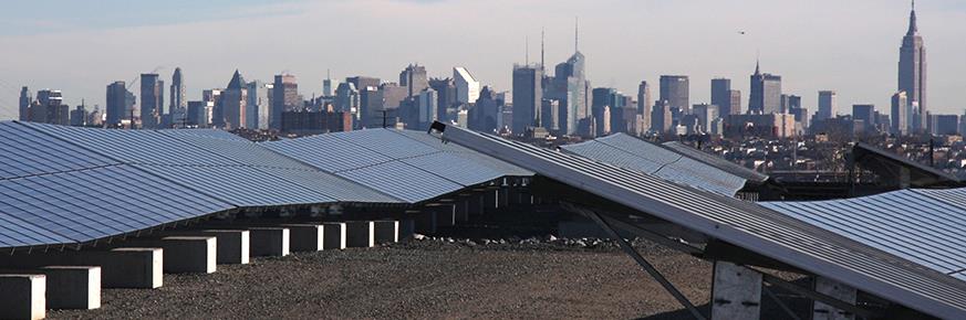 Two rows of solar panels on a New Jersey rooftop with the New York City skyline in the background