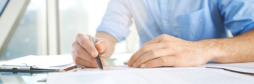 Torso & hands of person sitting at a table, writing on paper