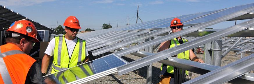 Two workers installing solar panels onto an elevated grid