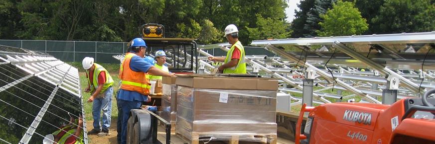 Work crew unloading solar panels from utility vehicle