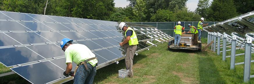 A group of workers in a filed installing solar panels as a photovoltaic array