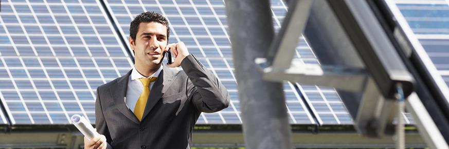 Man in suit with cellphone in front of solar panels